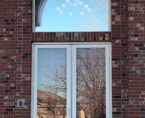 Old white double entry doors on a brick home